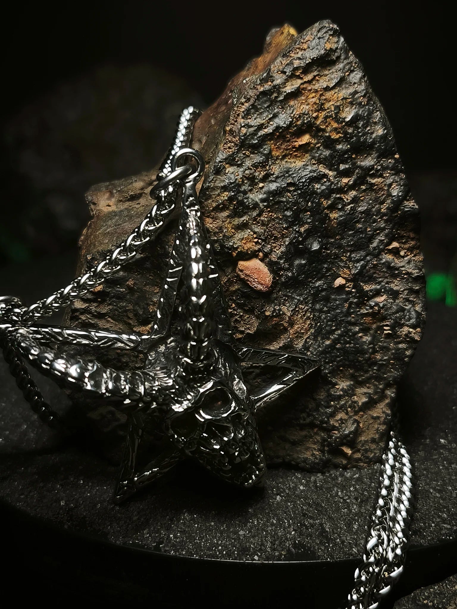Sello de Mendes: Detalle de cadena quirúrgica con amuleto esotérico de pentagrama invertido y calavera de acero en Chile.