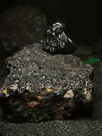 La Faz de Cthulhu: Vista lateral de anillo soberano del abismo de acero inoxidable sobre roca volcánica estilo dark en Chile.