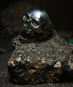 Reliquia del Devorador Steel: Vista lateral de anillo de calavera memento mori de acero inoxidable mostrando texturas de porosidad salvaje en Chile.