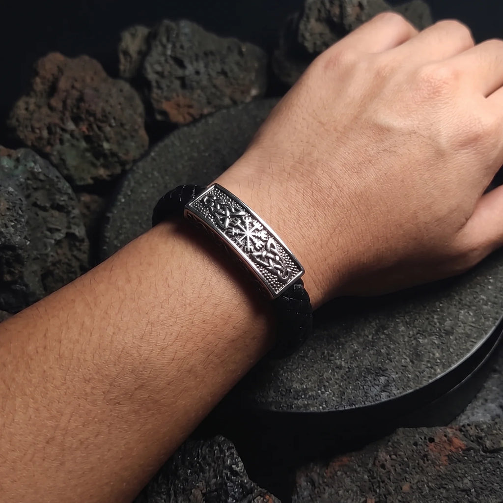 Vista de uso del brazalete vikingo Vegvísir de cuero sintético negro y placa de acero inoxidable tallada puesto en la muñeca.