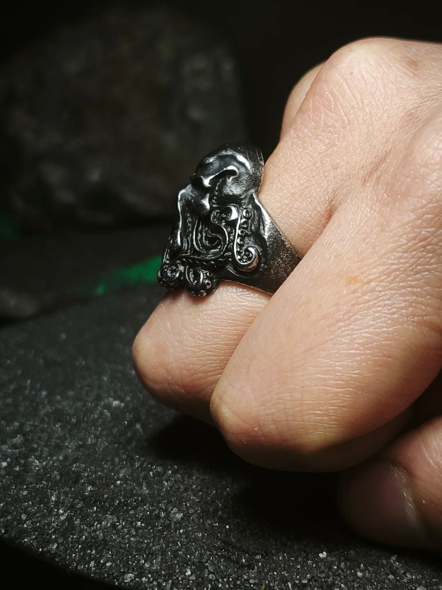 La Faz de Cthulhu: Vista de perfil de anillo de acero inoxidable con relieves de tentáculos de horror cósmico puesto en la mano en Chile.