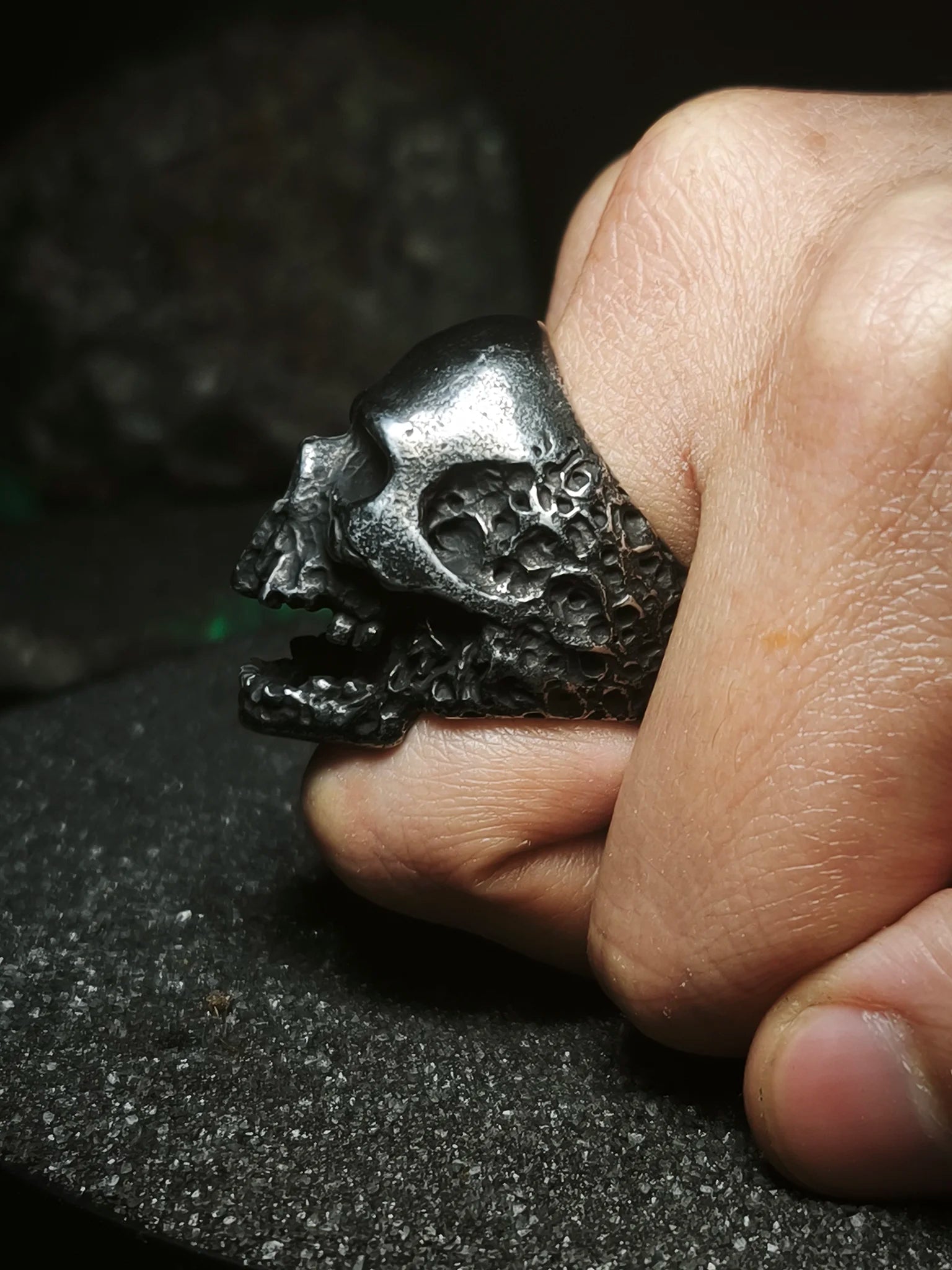 Reliquia del Devorador Antique: Anillo de calavera envejecido memento mori puesto en el dedo mostrando relieves de osario en Chile.