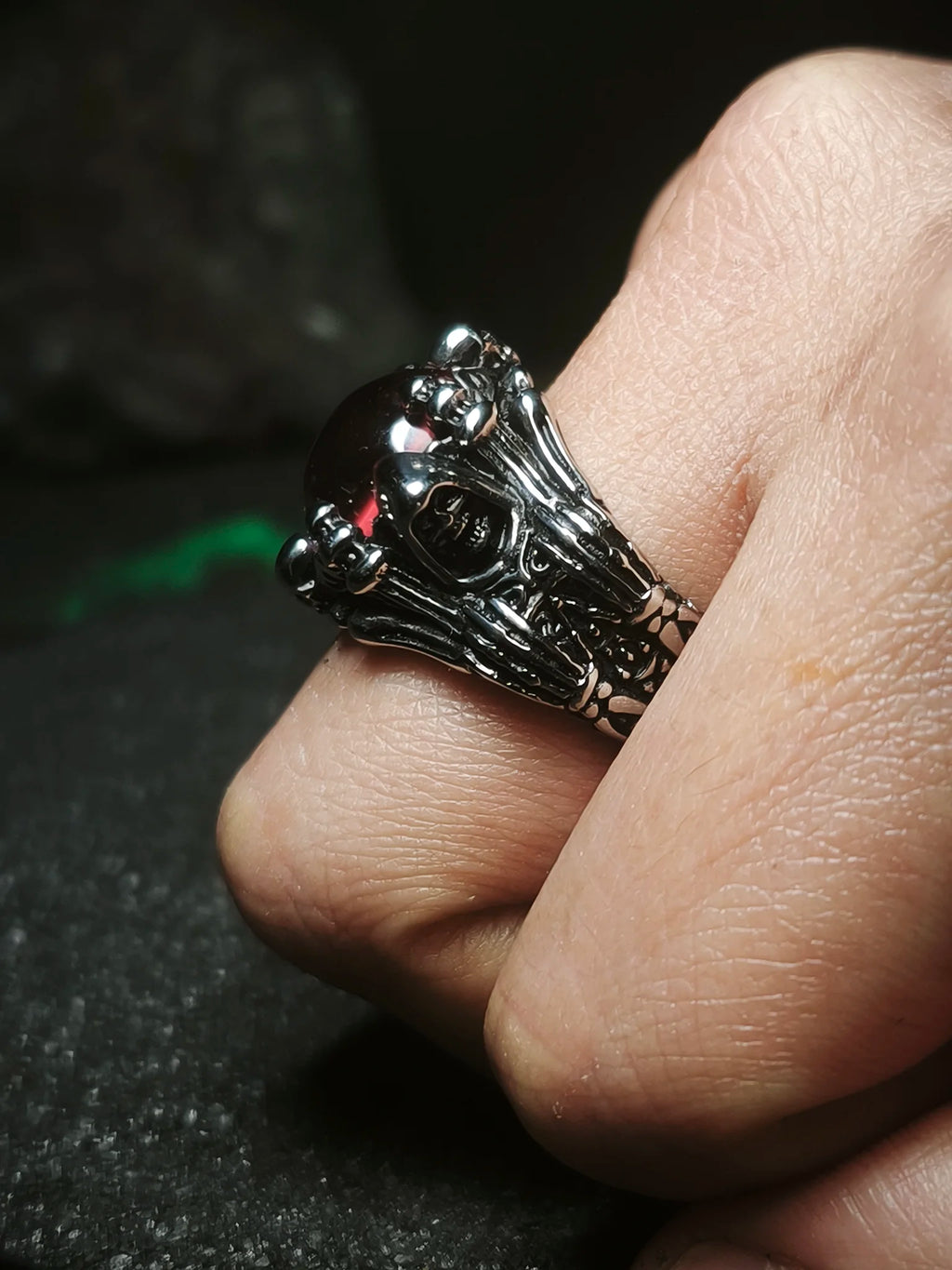 Vigía del Inframundo: Vista de perfil de anillo de acero inoxidable con garras esculpidas y gran orbe escarlata puesto en la mano en Chile.