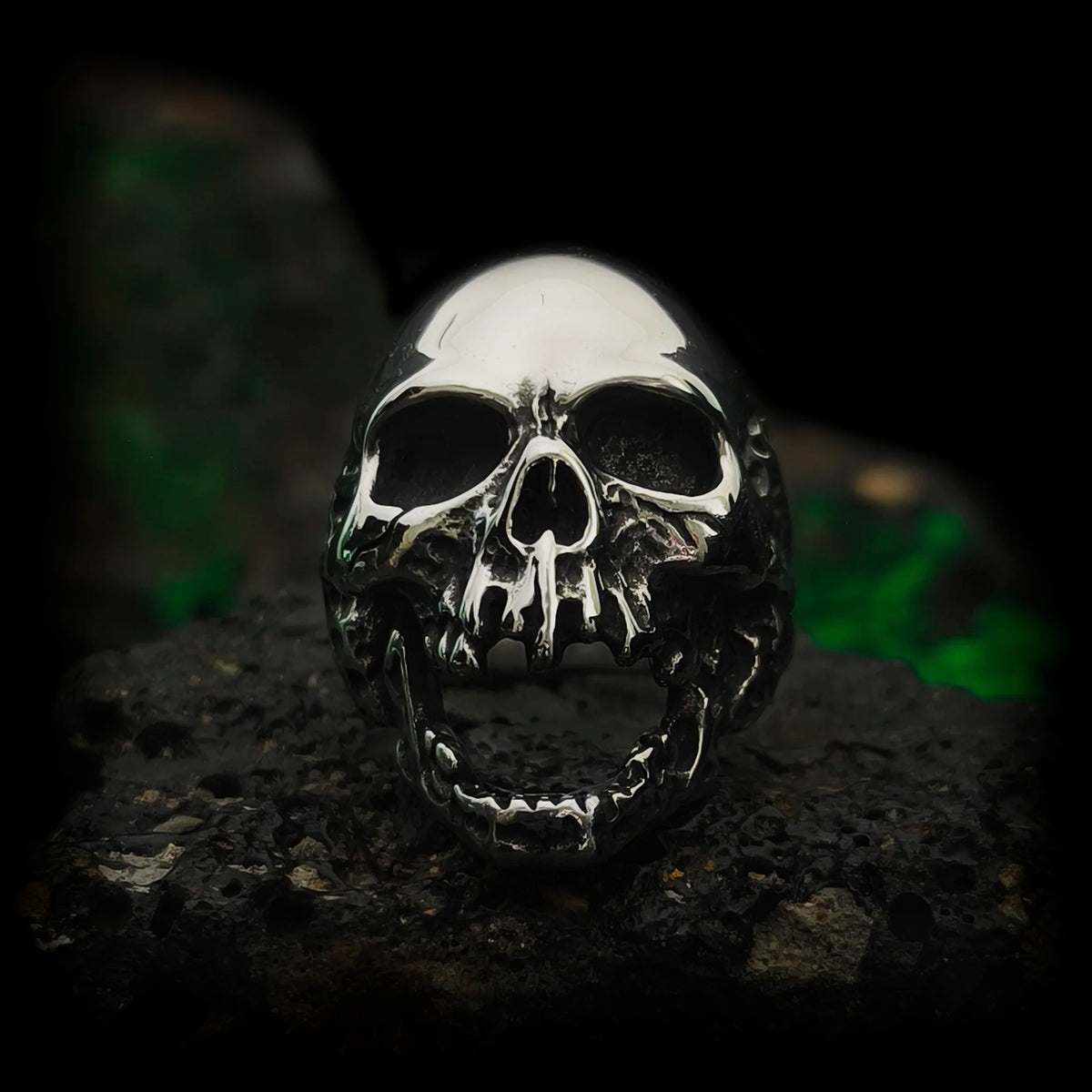 Anillo calavera gótico de acero El Clamor de Baudelaire, mandíbula abierta en vista frontal sobre roca | Abyssal Relics.