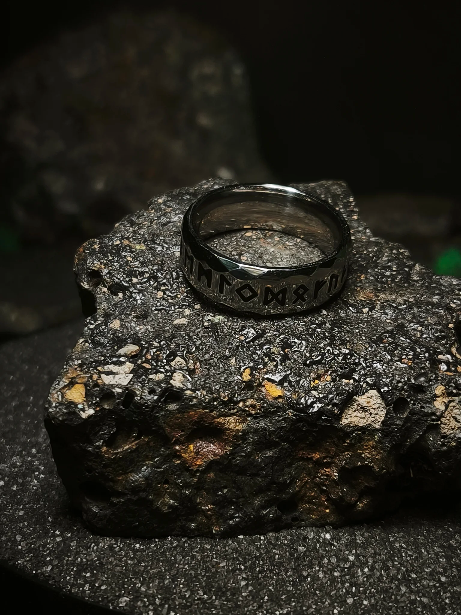 Legado de las Runas: Foto de portada de anillo vikingo facetado con grabado del alfabeto futhark en acero de alta densidad sobre roca volcánica en Chile.