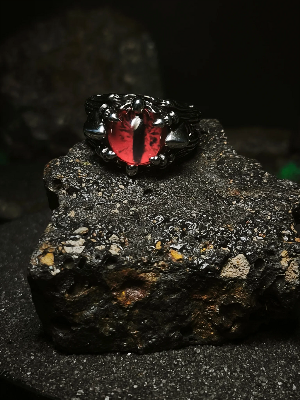 Vigía del Inframundo: Foto de portada de anillo ojo de la bestia con orbe escarlata brillante de pupila vertical y garras de acero en Chile.